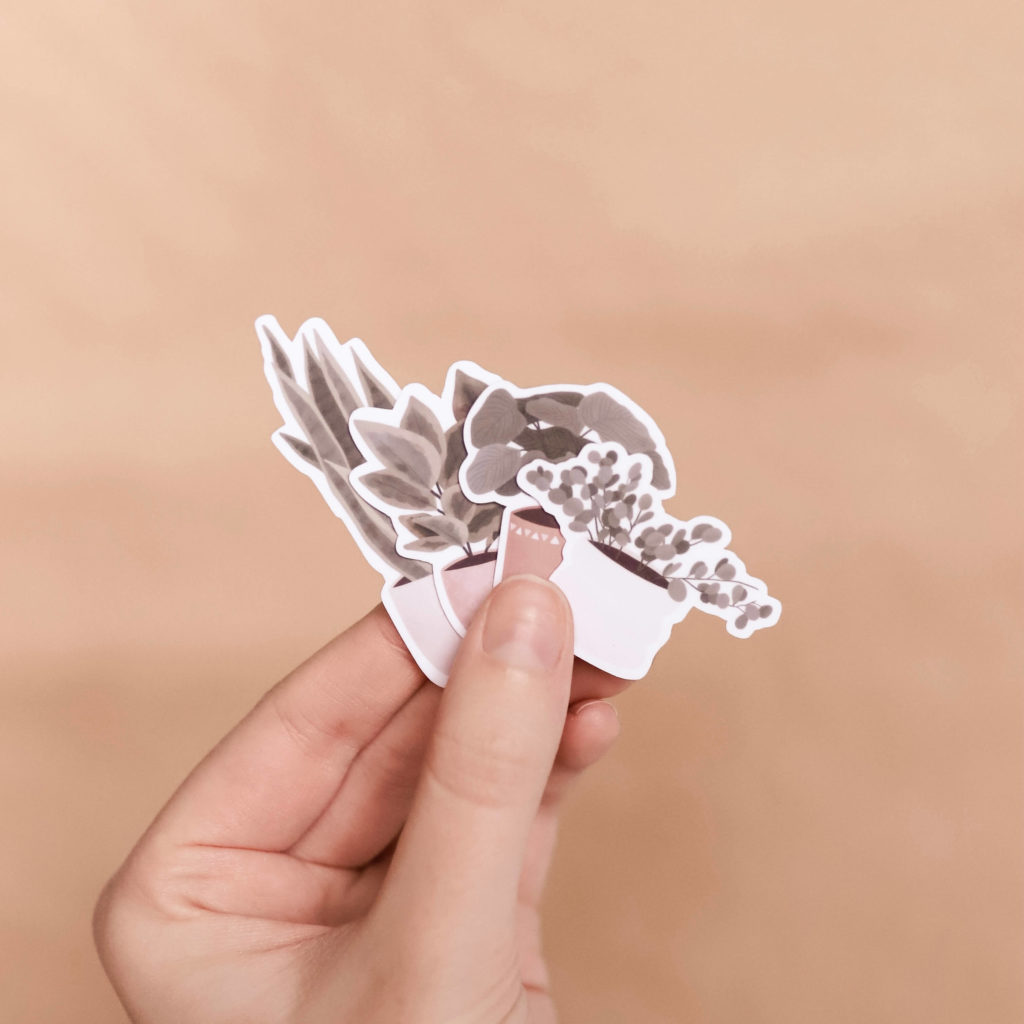 Hand holding waterproof plant stickers. Running a business on the side