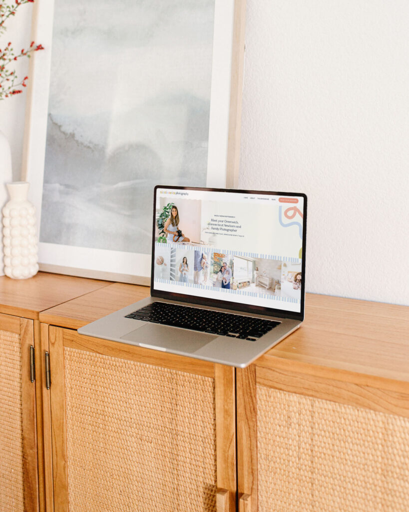 Computer sitting on light oak cabinet showing website design for Nicole Neria Photography