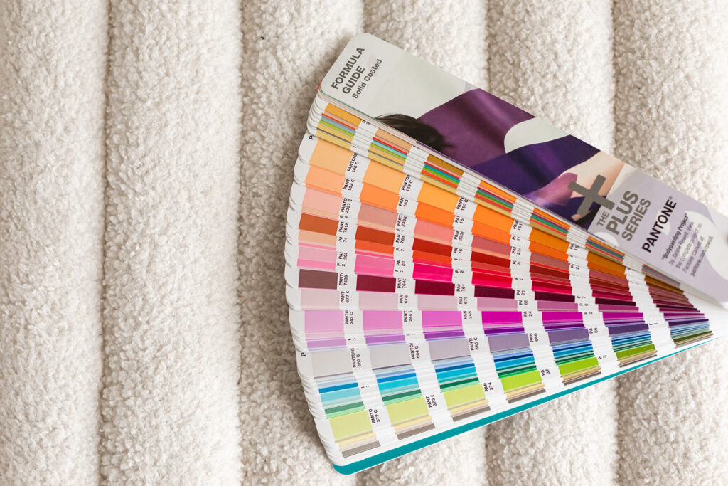 Colorful pantone swatch booklet sitting on sherpa ribbed cushion