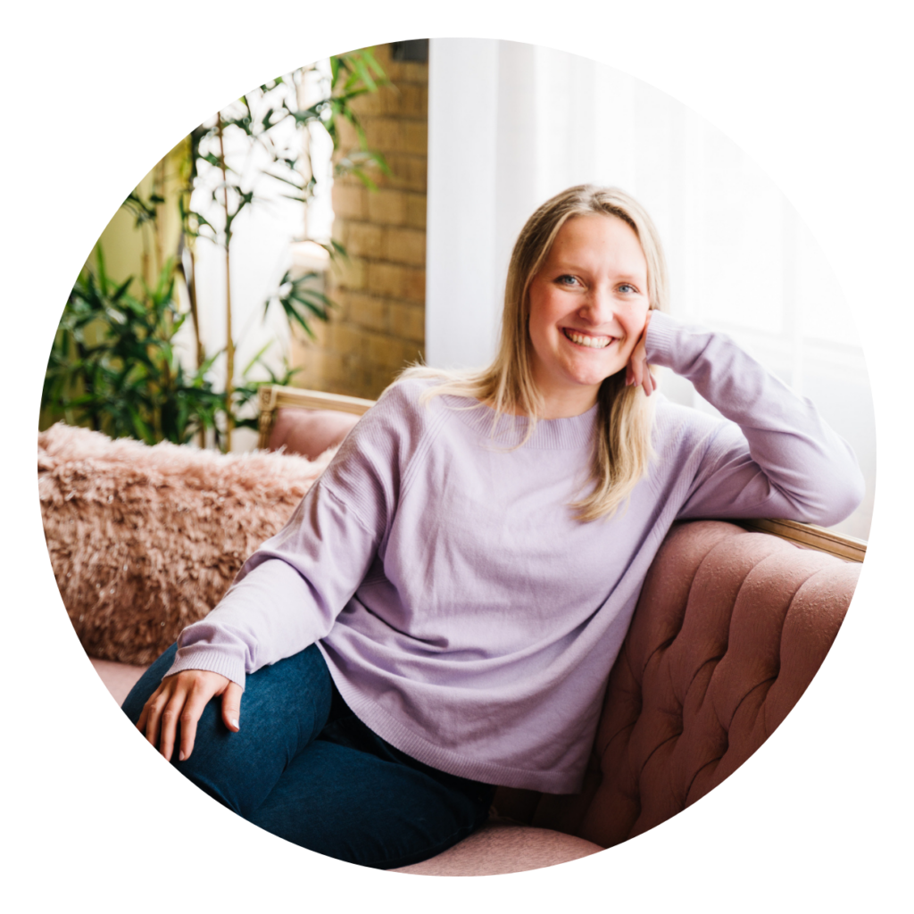 Woman with blonde hair wearing purple sweater sitting on brown leather couch