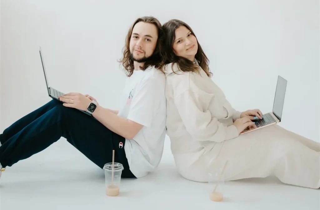 man and woman sitting on floor with laptops and iced coffees