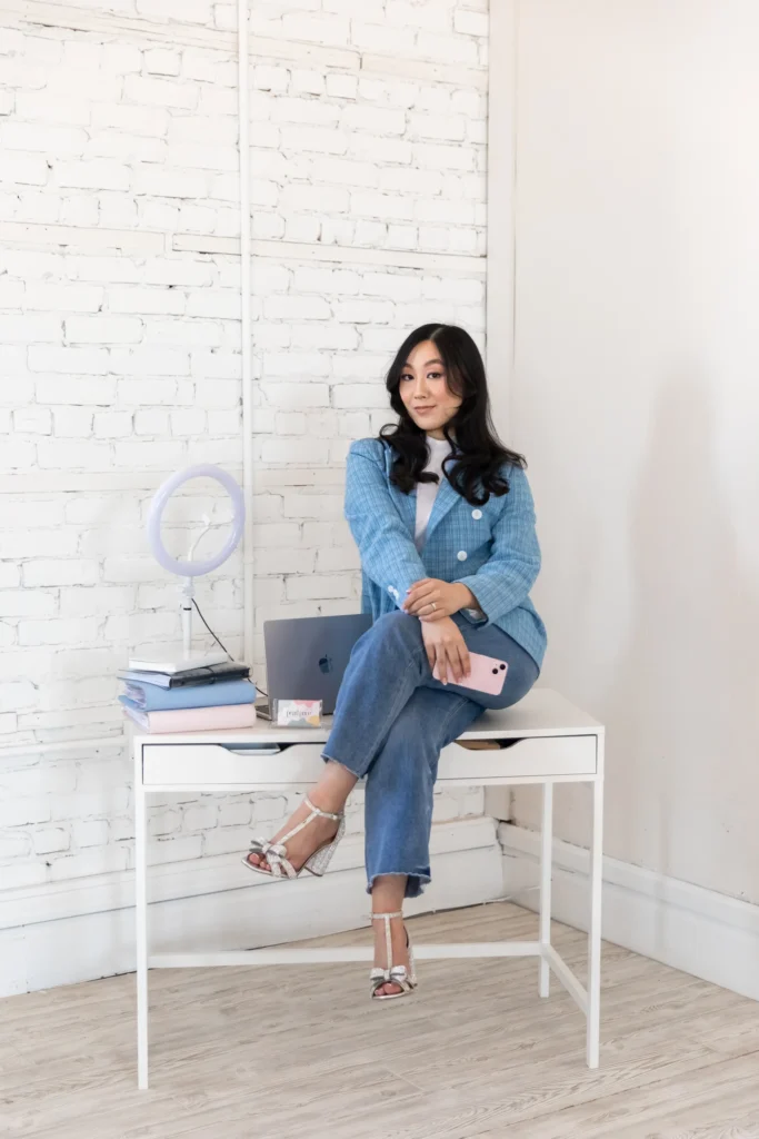 Woman wearing blue denim sitting on white desk in brightly lit room