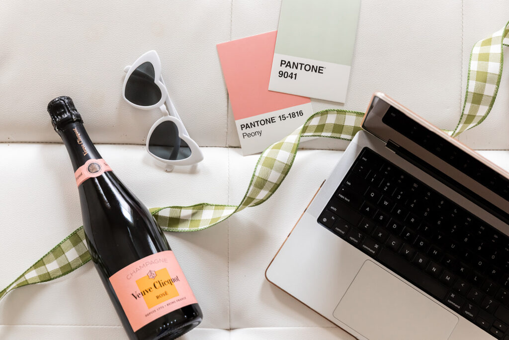 Laptop, sunglasses, color swatches, and champagne bottle laying on couch typography tips