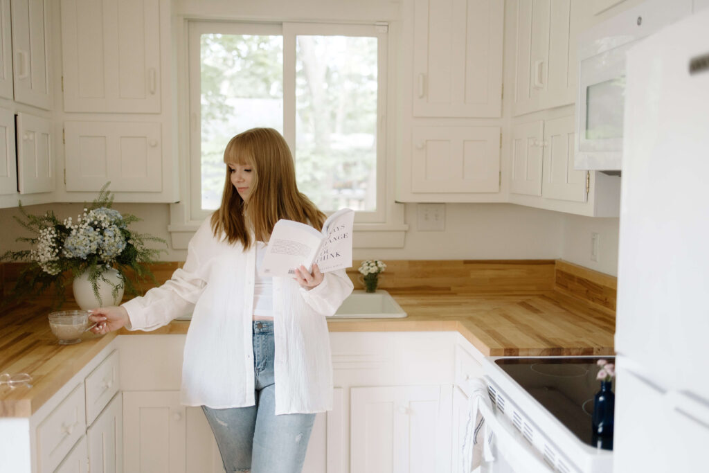 Woman with blonde hair wearing white button standing in a kitchen